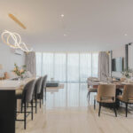 Kitchen island with seating area and sink next to dining table and living area